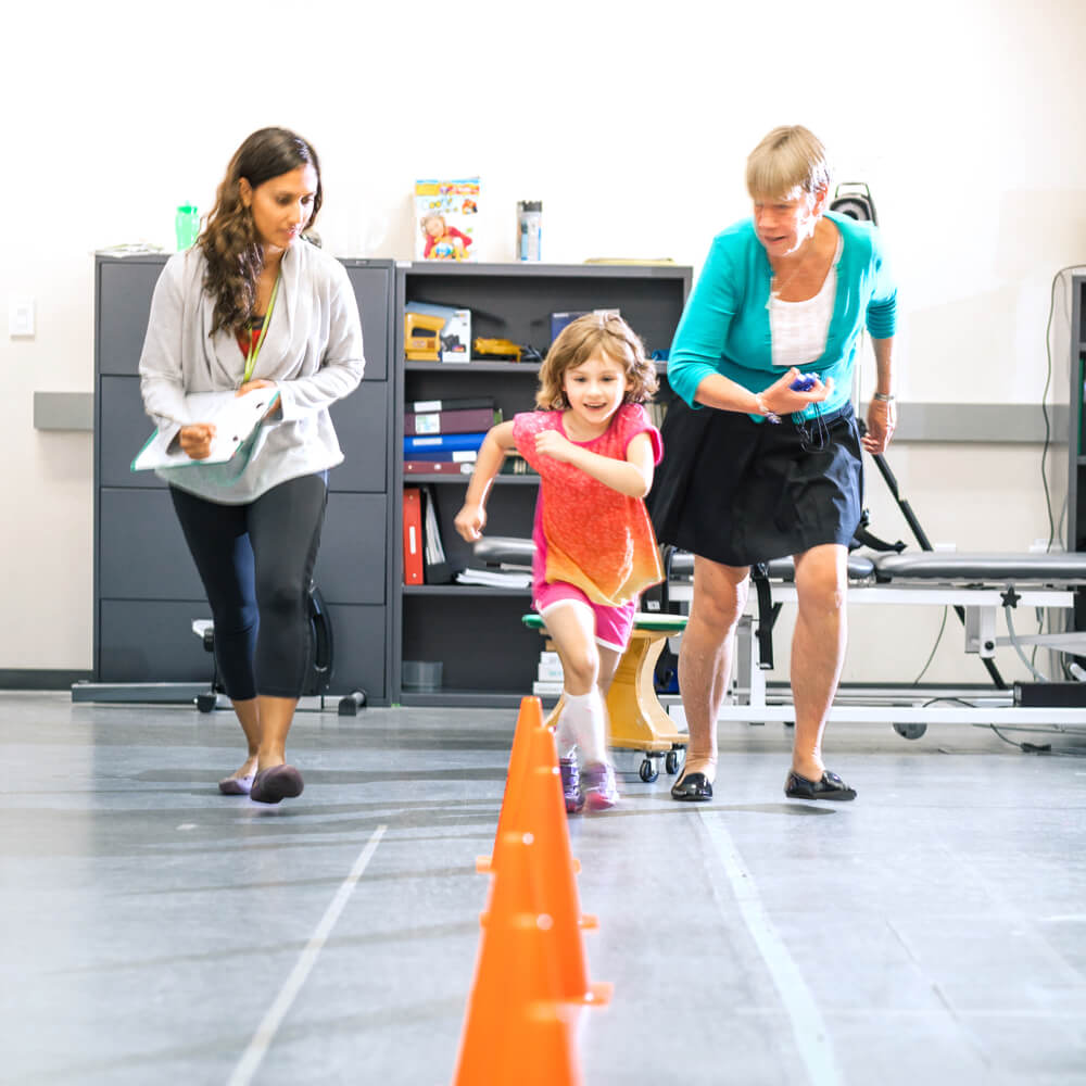 Two people timing a child running during a clinical trial